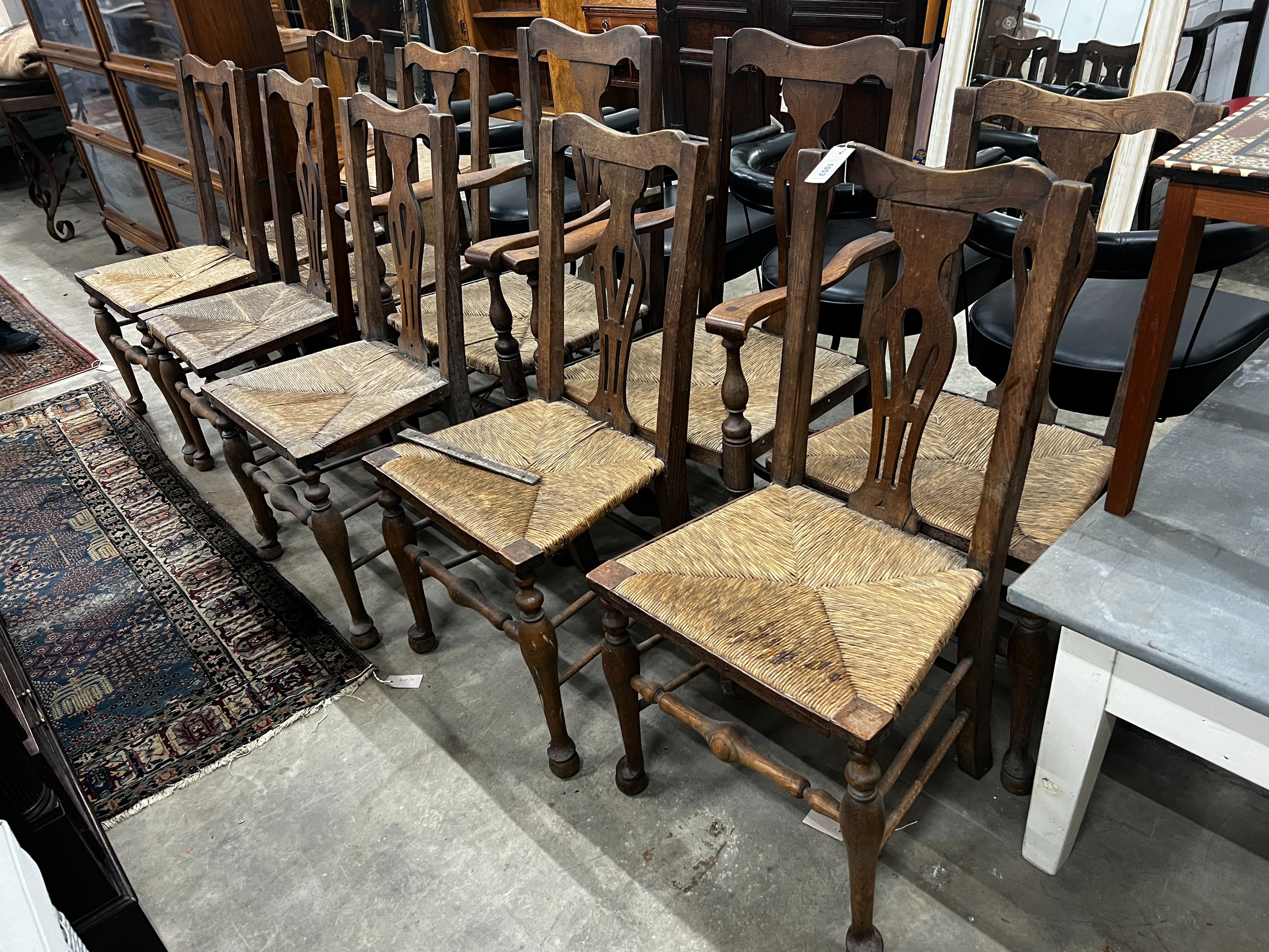 A set of ten George III style provincial oak rush seat dining chairs, two with arms.